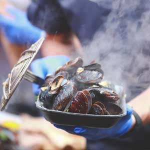 cooking fresh mouth-watering mussels by a chef at a food festival